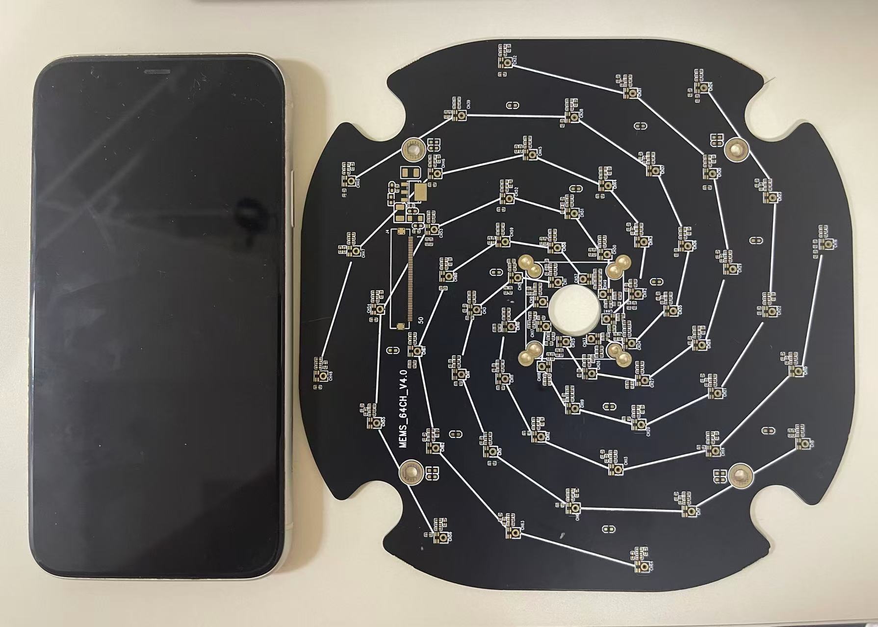 Original compact black PCB photograph with iPhone XR for scale