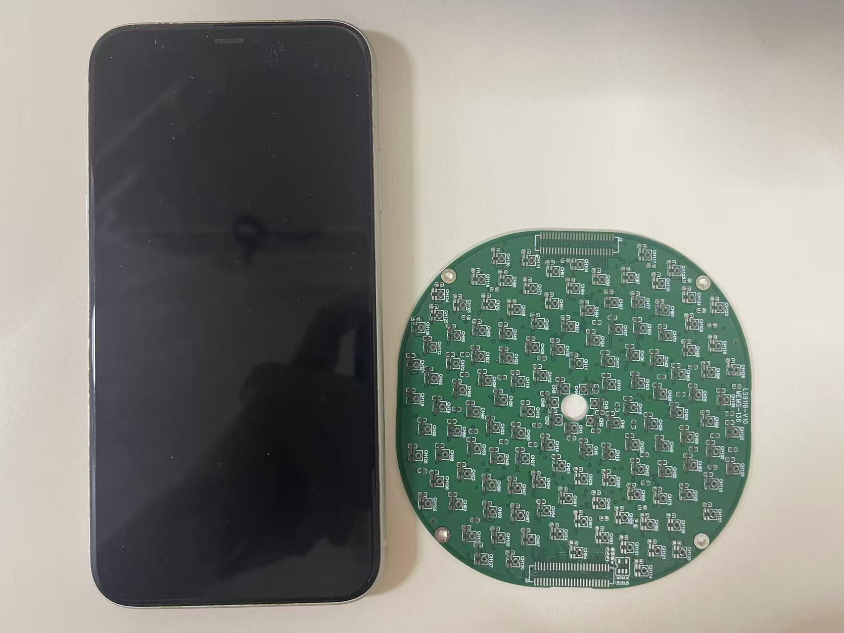 Original dense PCB photograph with iPhone XR for scale