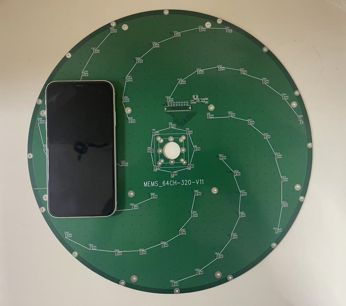 Original circular PCB photograph with iPhone XR for scale
